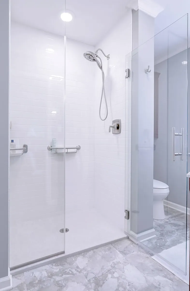 White solid-surface walk-in shower with frameless glass and a grab bar