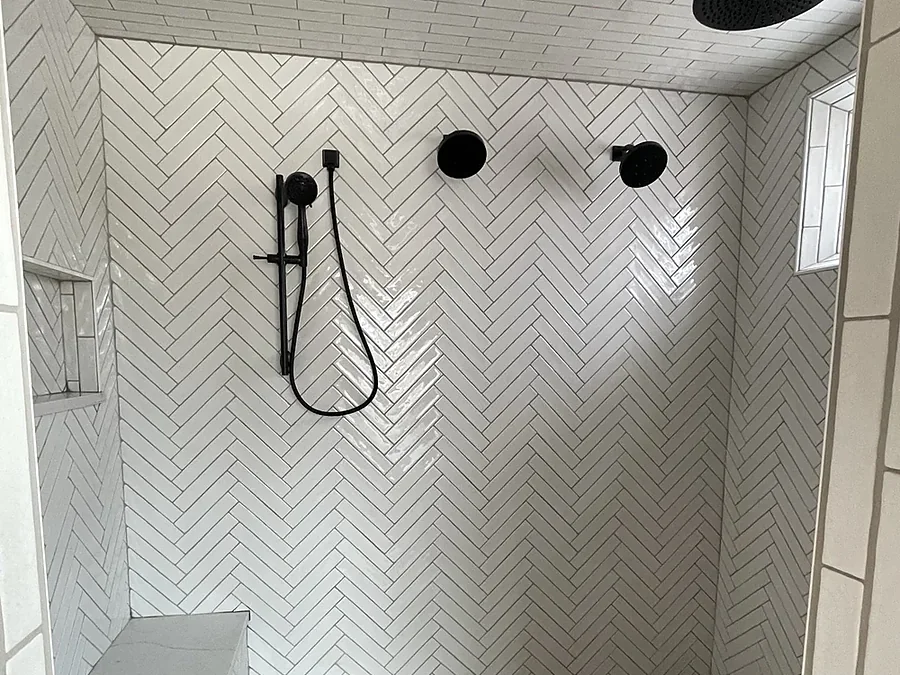 Walk-in shower with white herringbone tile, bench and matte black fixtures
